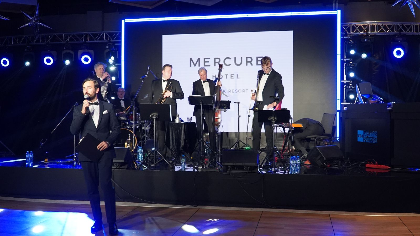 Konferansjer i zespół muzyczny w smokingach na scenie gali hotelowej