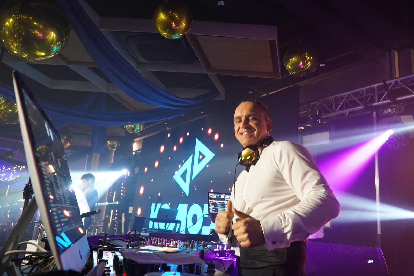 DJ za konsoletą na tle ekranów LED